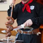 A traditionally dressed server brings meat on a skewer during a birthday at Gaucho Brazilian Barbecue