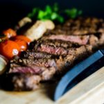 Steak and veggies and a knife on a cutting board indicative of where to eat in Canmore